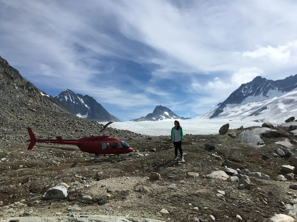 A guest beside the helicopter at the toe of a glacier on the Royal Glacier Tour