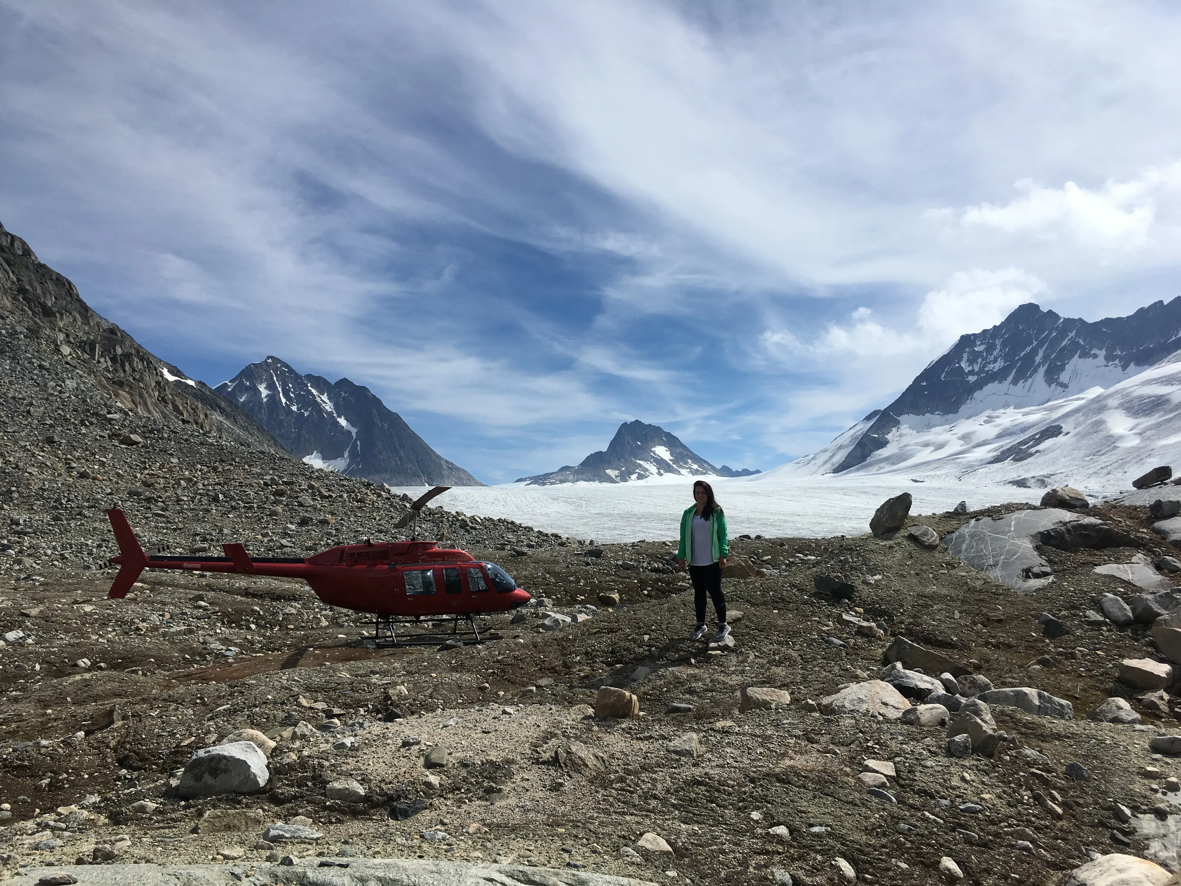 A guest beside the helicopter at the toe of a glacier on the Royal Glacier Tour